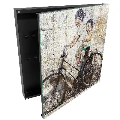 Boîte à clés murale art de rue représentant des enfants à vélo sur un vieux mur