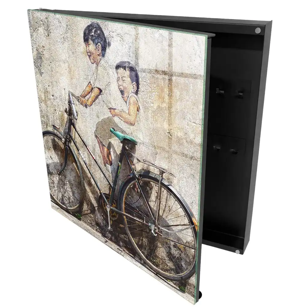 Boîte à clés murale art de rue représentant des enfants à vélo sur un vieux mur