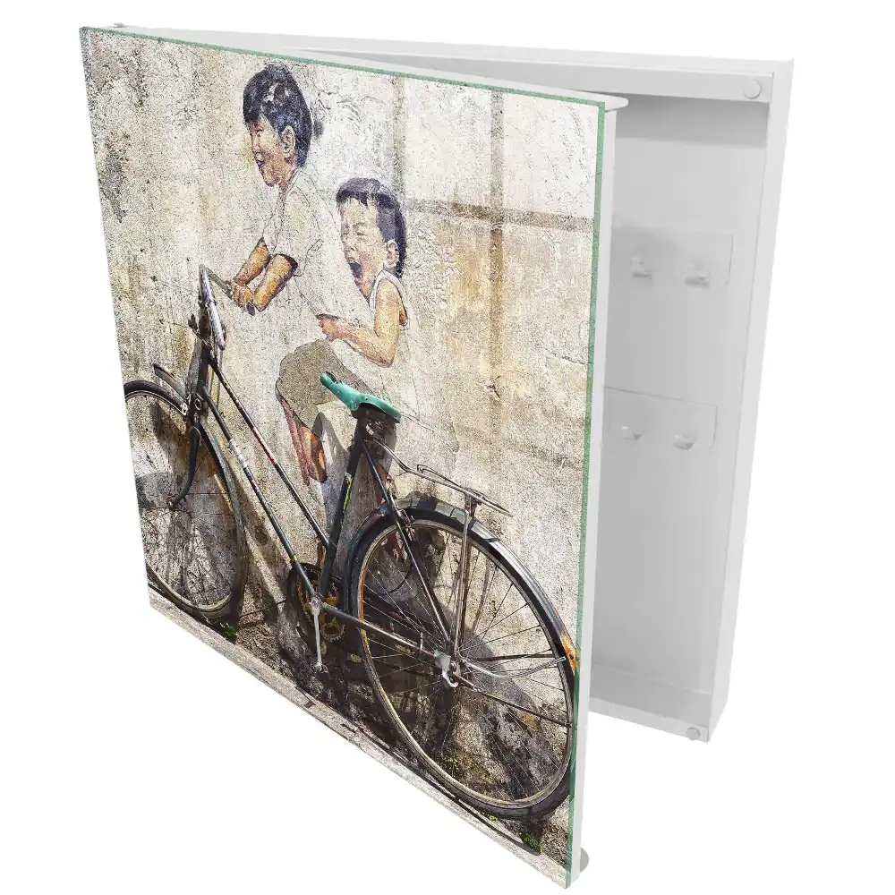 Boîte à clés murale art de rue représentant des enfants à vélo sur un vieux mur