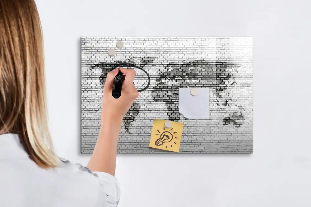 Tableau magnétique illustrant le monde sur fond de mur de briques