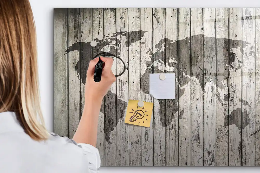 Tableau blanc magnétique effaçable à sec représentant une carte du monde sur fond de table en bois